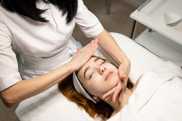 Young woman enjoying massage in spa salon. Face massage. Closeup of young woman getting spa massage treatment at beauty spa salon.Spa skin and body care. Facial beauty treatment.Cosmetology. . High qu