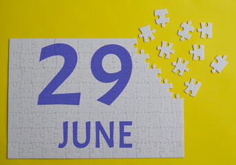 29 june calendar date on a white puzzle with separate details. Puzzle on a yellow background with a blue inscription