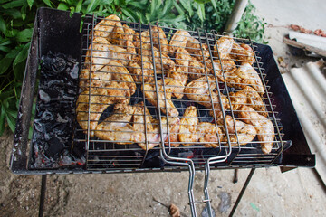 Spicy chicken wings marinated with spices and mustard are fried on coals on the grill