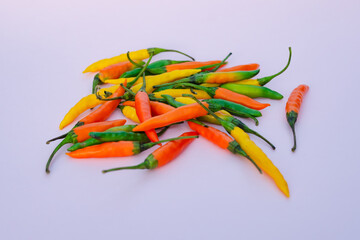 A bunch of colored hot chili peppers on a lilac background. The concept of agriculture and organic food