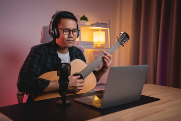 Asian man youtuber live streaming perfomance playing guitar and sing a song. Asian man teaching...