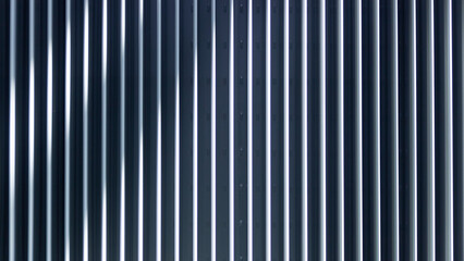 Corrugated metal painted with gray paint with reflections of sunlight