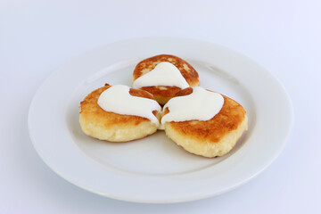 Delicious, ruddy cheesecakes covered with sour cream on a white plate.
