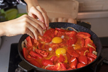 crack an egg into a frying pan with tomatoes