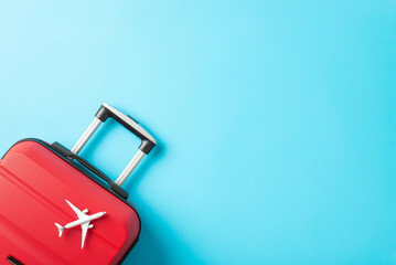 Ready for New Year's Getaway: Top view photograph of a red suitcase, and miniature plane against a...