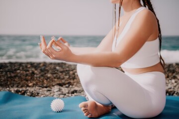 Close up Yoga Hand Gesture of Woman Doing an Outdoor meditation. Blurred sea background. Woman on yoga mat in beach meditation, mental health training or mind wellness by ocean, sea. Selective focus
