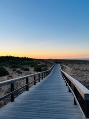 Boardwalk to the ocean, orange horizon, blue pure sky, no people