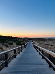 Boardwalk to the ocean, orange horizon, blue pure sky, no people