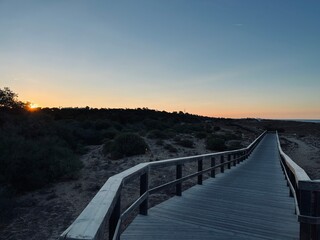 Boardwalk to the ocean, orange horizon, blue pure sky, no people