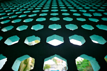 Abstract view of perforated wall made in concrete with hexagonal holes.