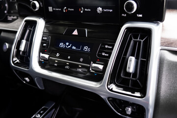 Air conditioning red button inside a car. Climate control AC unit in the new car. Modern car black leather interior details.