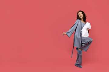 A girl with a pillow on a pink background.