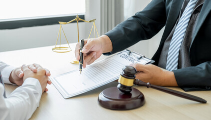 Lawyer hand holding pen and providing legal consult business dispute service at the office with justice scale and gavel hammer