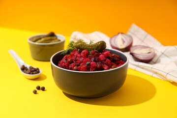 Salad vinaigrette and cucumbers in bowls, onion on yellow background