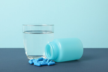 A glass of water with blue pills