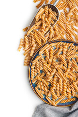 Raw whole grain fusilli pasta. Uncooked pasta on plate isolated on white background.