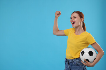 Emotional fan holding football ball and celebrating on light blue background, space for text