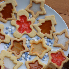 Christmas cookies with fake “glass” made of melted candies on plate on wooden table with festive decorations