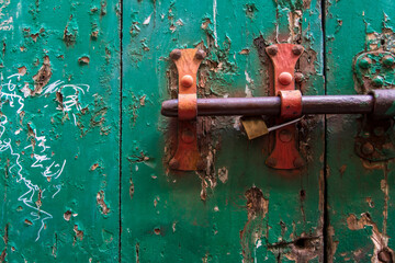 Dettaglio di un chiavistello arrugginito su una vecchia porta di legno dipinta di verde