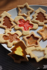 Christmas cookies with fake “glass” made of melted candies on plate on wooden table