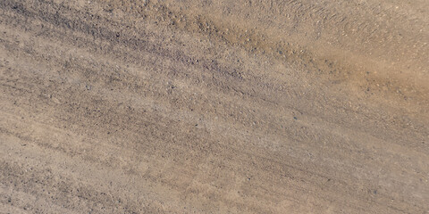 panorama of road from above on surface of gravel road with car tire tracks in countryside