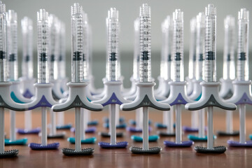 Collection of dermal tuberculin syringes in a row on wooden background. Colorful filler syringes decorating aesthetic clinic or salon. Beauty concept
