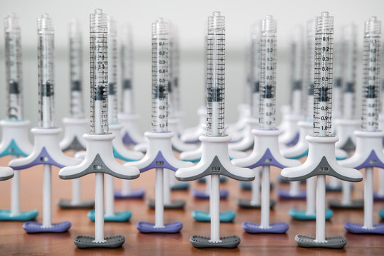 Collection of dermal tuberculin syringes in a row on wooden background. Colorful filler syringes decorating aesthetic clinic or salon. Beauty concept