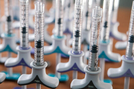 Close up of many dermal tuberculin syringes in a row on wooden background. Colorful filler syringes decorating aesthetic clinic or salon. Beauty concept
