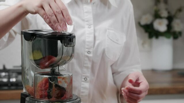 a woman makes tomato juice for the family using a juicer. Healthy lifestyle concept.