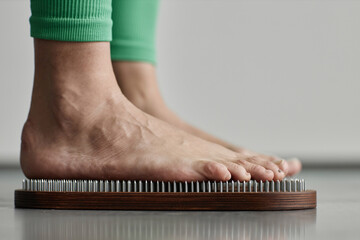 Side view macro shot of bare feet standing on nail board in yoga studio, copy space