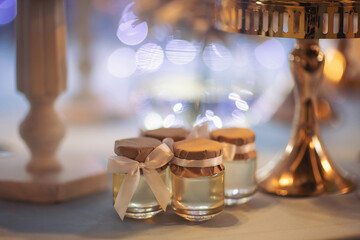 Small honey bottle with ribbon. Honey bonbonniere on served for wedding table. Wedding favors of...