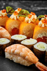 Set of different sushi rolls on a black board. Assorted Japanese sushi with salmon, eel, shrimp