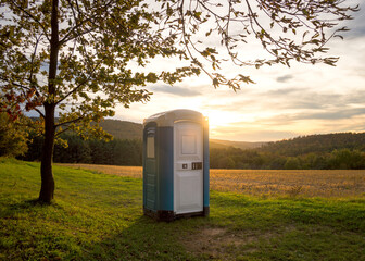 blue plastic toilet cabin in woodland at sunset - 675216379