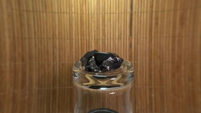 Shungite on a jar against a brown raffia background