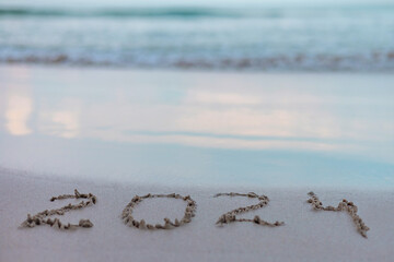 handwritten inscription 2024 on the sand by the sea