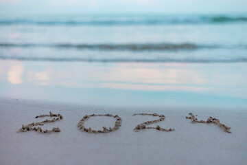 handwritten inscription 2024 on the sand by the sea