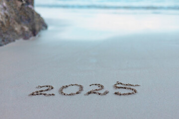 handwritten inscription 2025 on the sand by the sea
