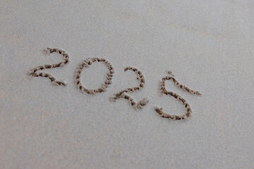 handwritten inscription 2025 on the sand by the sea