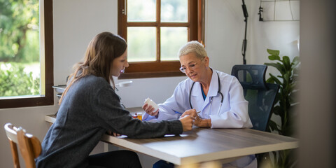 Medicine, healthcare and people concept female doctor with medicine bottle talking to women patient...