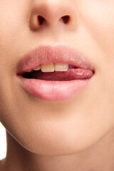 Obraz premium Open mouth, tongue touches teeth. Close up view of woman licking pink natural gloss lips. Beautiful plump lips.