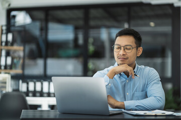 Fototapeta premium Businessman using laptop computer in office. Happy man, entrepreneur, small business owner working online.