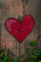 Un cuore rosso dipinto su un tronco di legno di una staccionata