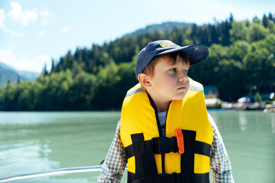 boy wearing safety vest feel sick sailing paddleboat on beautiful Lake. mountains on background