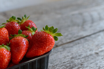 Ripe strawberries in a black box on a wooden table. High quality photo