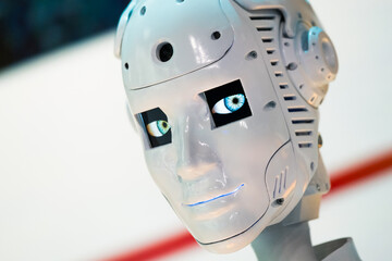 Closeup of white illuminated human robot looking camera against blurred background