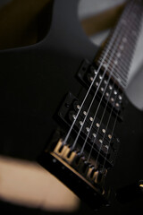 Part of a black electric guitar, strings close. Musical instruments, learning to play the guitar