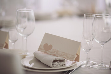 festive tables at the wedding party, on the tables are plates with napkins and cards, glasses. elegant dinner table setting in restaurant or hotel.