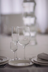 Set of empty glasses and dishware on table indoors. Transparent glasses on glossy shelf in luxury restaurant. Empty champagne glasses before the ceremony