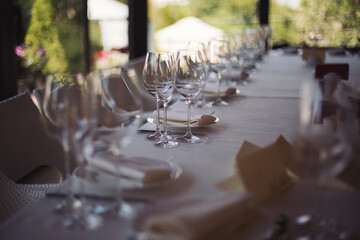 elegant dinner table setting in restaurant or hotel with wine glasses. tableware Glasses, flower fork, knife served for dinner in restaurant