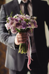 wedding bouquet of flowers in the hands of the groom. Beautiful wedding bouquet of flowers. The groom holds in his hand a bouquet for the bride. Beautiful wedding bouquet color luxury romantic